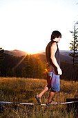 A professional slackliner plays around on the slackline in a field at sunset in the Blue Mountain of Missoula, Montana Missoula, Montana, USA