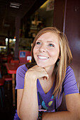 Young, woman sitting in a diner looks away and smiles Julian, California, USA