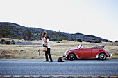 Young lady jumps in the arms of her boyfriend on the road by their retro car Julian, California, USA