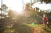 Young girl swings on a swing while her friends pose for the camera San Diego, California, USA