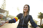 Young woman wearing a hoodie rides a cruiser bike Coronado, California, USA