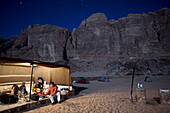 Three climbers organize gear in tent under starry sky Wadi Rum Village, Jordan