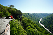 Woman and her dog take in the view from a high mountain cliff Fayetteville, West Virginia, USA