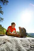 Woman stretches on a mountaintop before trail running in a lush green forest Fayetteville, West Virginia, USA