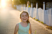 A freckled girl is smiling with a picket fence and sun in the background Destin, Florida, USA