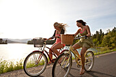 Women ride beach cruisers next to the lake in Idaho Sandpoint, Idaho, USA