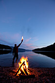 Lone figure stands behind campfire in Idaho Sandpoint, Idaho, USA