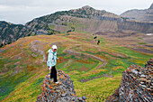 A young woman stands on a rock overlooking a colorful field on Mt. Timpanogos, near Pleasant Grove, UT Pleasant Grove, Utah, USA