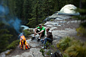 Two young men sit around a fire on a camping trip in Idaho Sandpoint, Idaho, USA