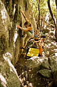 Protected by her friends spotting below, a woman boulders in Utah's Wasatch Mountains Utah, USA