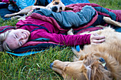 A woman curls up with her dogs during a summer sleep out Utah, USA