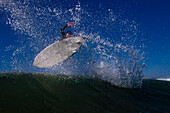 A male surfer does an air while surfing in Malibu, California Malibu, California, United States of America