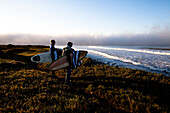 Two young male surfers hike along a trail Ventura, California, United States of America