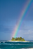 A brilliantly colored rainbow falling over a small desert island Hawaii, USA
