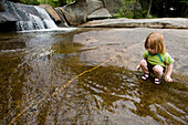 A young girl plays near a waterfall Newry, Maine, USA