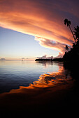Colorful clouds light up the sky in a sunset over ocean in Tahiti, Teahupoo, Tahiti