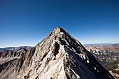 Two young men crossing an exposed ridge line with the summit behind them Aspen, Colorado, USA