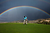 A golfer putts under an amazing double rainbow in Colorado Vail, Colorado, USA