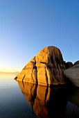 A large granite boulder is illuminated at sunset on the east shore of Lake Tahoe, NV Lake Tahoe, Nevada, USA