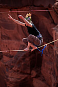 A female highliner stands up on a highline at the Fruit Bowl in Moab, Utah, USA Moab, Utah, United States