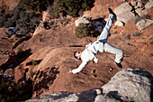 Man in pinned stripe suite falling off a cliff Moab, Utah, United States