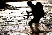 Male hiker crosses a stream late in the day in the Tetons Jackson Hole, Wyoming, USA