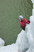 Woman climbing ice above water, Ouray, Colorado Ouray, Colorado, USA