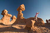 Young girl jumping off rocks in Goblin Valley State Park, Hanksville, Utah Hanksville, Utah, USA