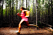 Woman jogging through a thick forest Jackson Hole, Wyoming, United States