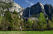 A young woman enjoys the great view of Yosemite Falls during a morning run in Yosemite National Park, California Yosemite, California, USA