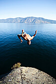 A young man back flips off a cliff into a lake in Idaho., Sandpoint, Idaho, USA