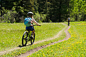 A young girl mountain biking through a meadow, Telluride, Colorado., Telluride, Colorado, usa