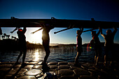 The Lake Casitas Rowing Team carries their boat down a dock at Lake Casitas in Ojai California., Ojai, California, United States of America