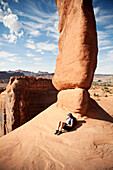 A female hiker rests against Delicate Arch in Arches National Park, Utah., Moab, UT, usa