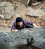 A male rock climber with a beard grimaces while he struggles to grab a hold., Erving, MA, USA