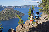 Hikers along cliff trail near lake Crater Lakes National Park, Oregon, United States