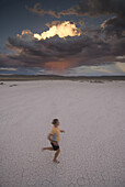 Woman runs on dry lake bed in desert Utah, United States
