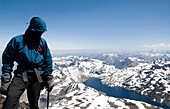 A climber stands at the summit of a peak in the Andes Mountains Chile