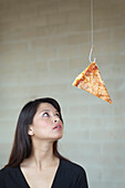 Asian woman looking at pizza on hook, Richmond, VA