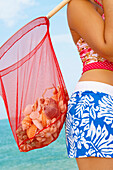 Woman carrying net full of seashells, Cape Cod, MA