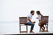 South American couple with wine on dock, Morrocoy, Venezuela