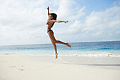 South American woman jumping on beach, Morrocoy, Venezuela