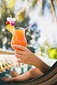 Asian woman with cocktail in hammock, Hilo, HI