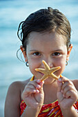 Hispanic girl holding starfish, Morrocoy, Venezuela