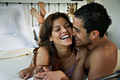 Hispanic couple laughing on bed, Morrocoy, Venezuela
