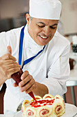 Hispanic male pastry chef decorating cake, Orlando, FL