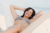 Cuban woman laying in hammock on beach, Fort Lauderdale, FL