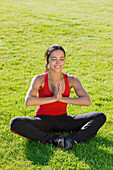 Hispanische Frau übt Yoga im Gras, Seattle, WA
