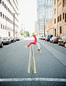 Hispanic teenage boy doing back flip in urban street, Jersey City, NJ