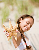 Hispanic girl holding starfish, Rockaway Beach, NY